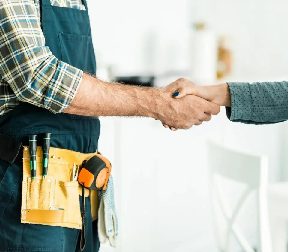 Cropped image of plumber and client shaking hands